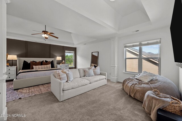 carpeted bedroom featuring a tray ceiling and ceiling fan