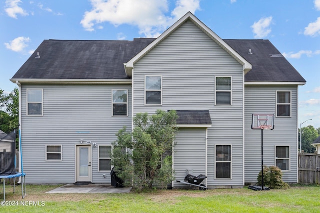 rear view of house with a patio area, a yard, and a trampoline