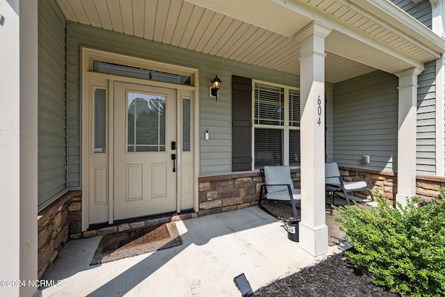 entrance to property with stone siding and a porch