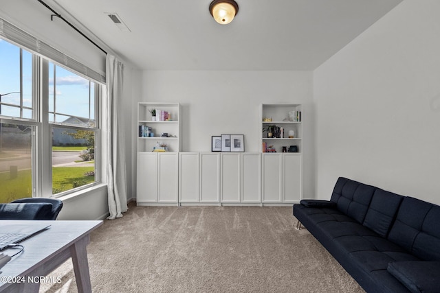 interior space with built in shelves, visible vents, a wealth of natural light, and light colored carpet