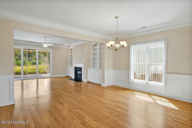 unfurnished living room featuring ceiling fan with notable chandelier, ornamental molding, light hardwood / wood-style flooring, and built in shelves