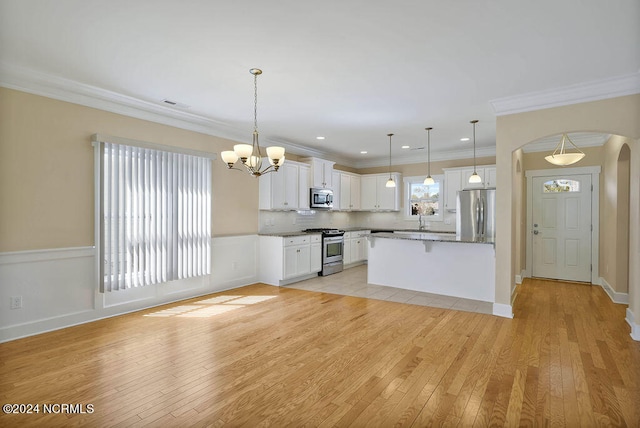 kitchen with decorative light fixtures, white cabinets, stainless steel appliances, and light hardwood / wood-style flooring