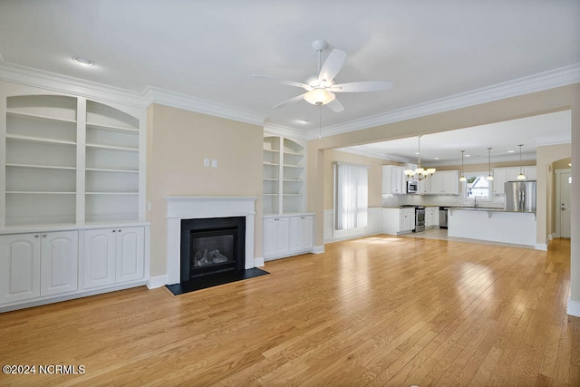 unfurnished living room featuring ceiling fan with notable chandelier, light wood-type flooring, crown molding, and built in shelves