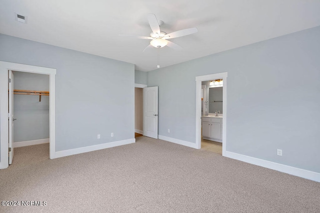 unfurnished bedroom with light colored carpet, ceiling fan, and a spacious closet