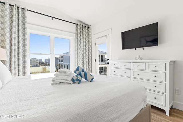 bedroom with light wood-type flooring, access to outside, multiple windows, and vaulted ceiling