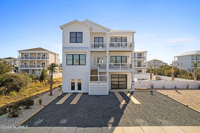 view of front of house featuring board and batten siding, french doors, fence, and a balcony