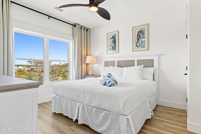 bedroom featuring light wood-style floors, baseboards, visible vents, and ceiling fan