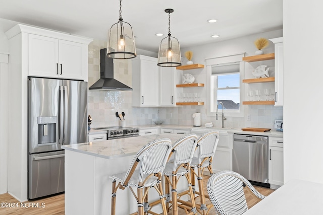 kitchen with appliances with stainless steel finishes, wall chimney range hood, white cabinetry, open shelves, and backsplash