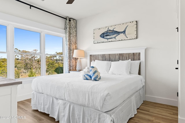 bedroom with ceiling fan, wood finished floors, and baseboards