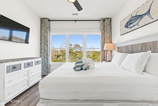 bedroom featuring a ceiling fan, visible vents, and wood finished floors