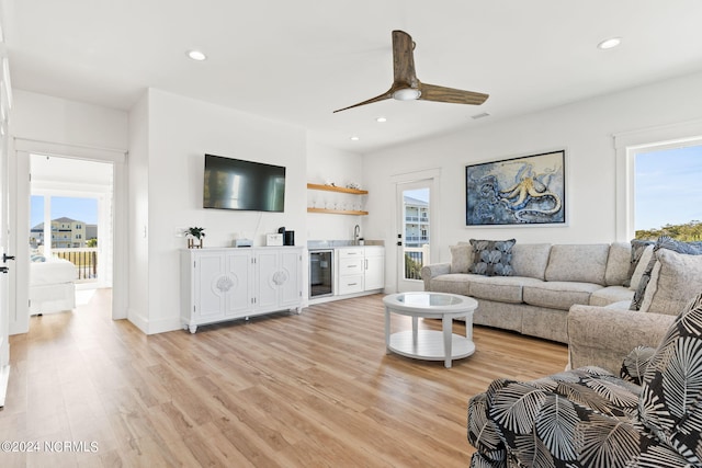 living room featuring light wood-style floors, recessed lighting, beverage cooler, and indoor wet bar