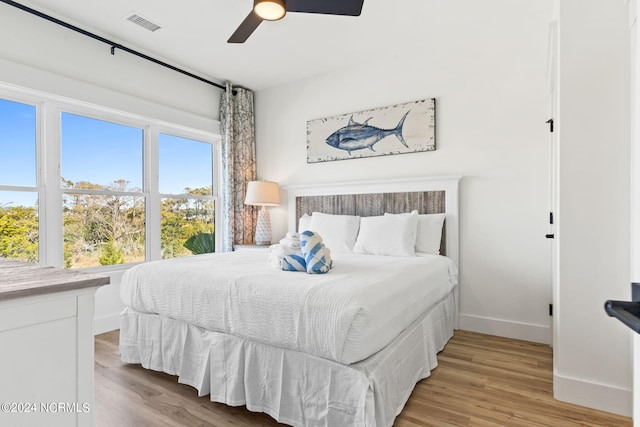 bedroom featuring a ceiling fan, visible vents, light wood-style flooring, and baseboards