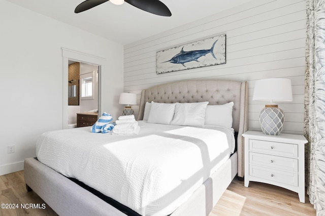 bedroom with light wood-style floors, ceiling fan, wood walls, and baseboards