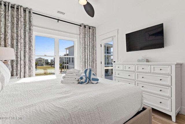 bedroom with access to exterior, visible vents, light wood-style flooring, and a ceiling fan