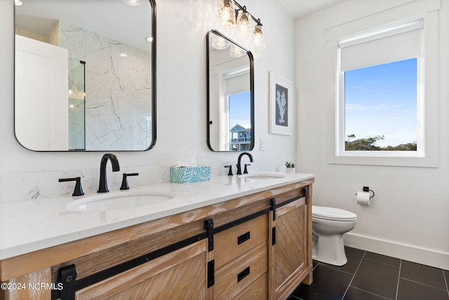 full bath featuring a marble finish shower, double vanity, a sink, and toilet