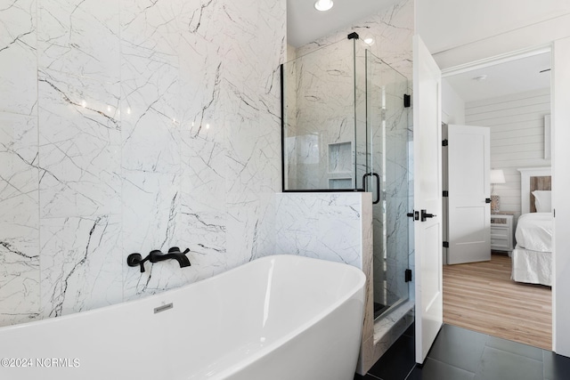 bathroom with a freestanding tub, tile walls, a marble finish shower, and ensuite bathroom