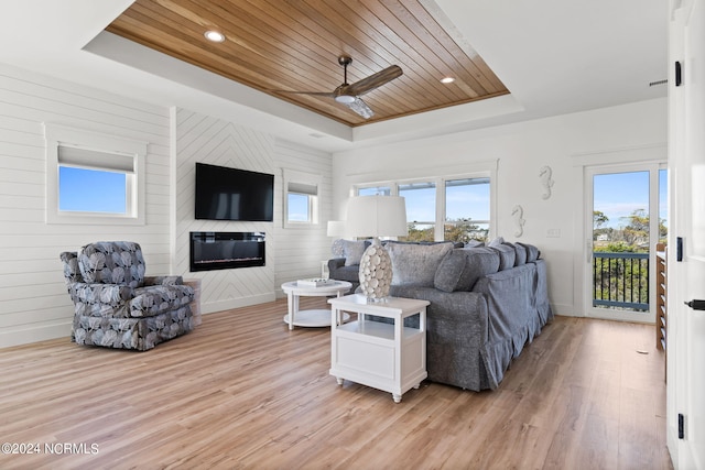 living area featuring plenty of natural light, a raised ceiling, wood ceiling, light wood-type flooring, and a fireplace