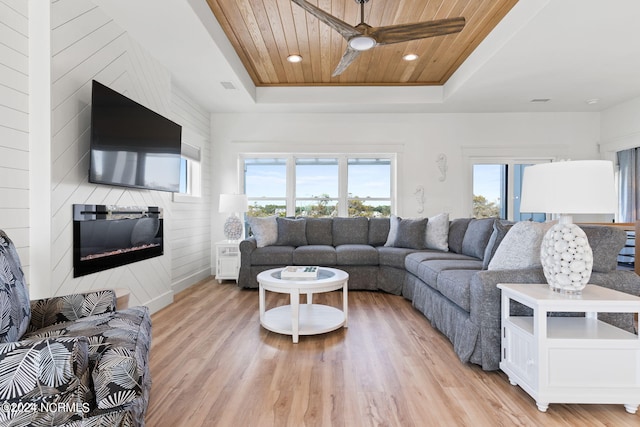 living area with recessed lighting, a raised ceiling, light wood-style floors, a large fireplace, and wooden ceiling