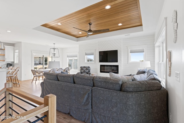 living area featuring light wood-style flooring, a raised ceiling, and wood ceiling