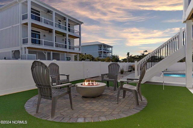 patio terrace at dusk featuring a fenced backyard and a fire pit