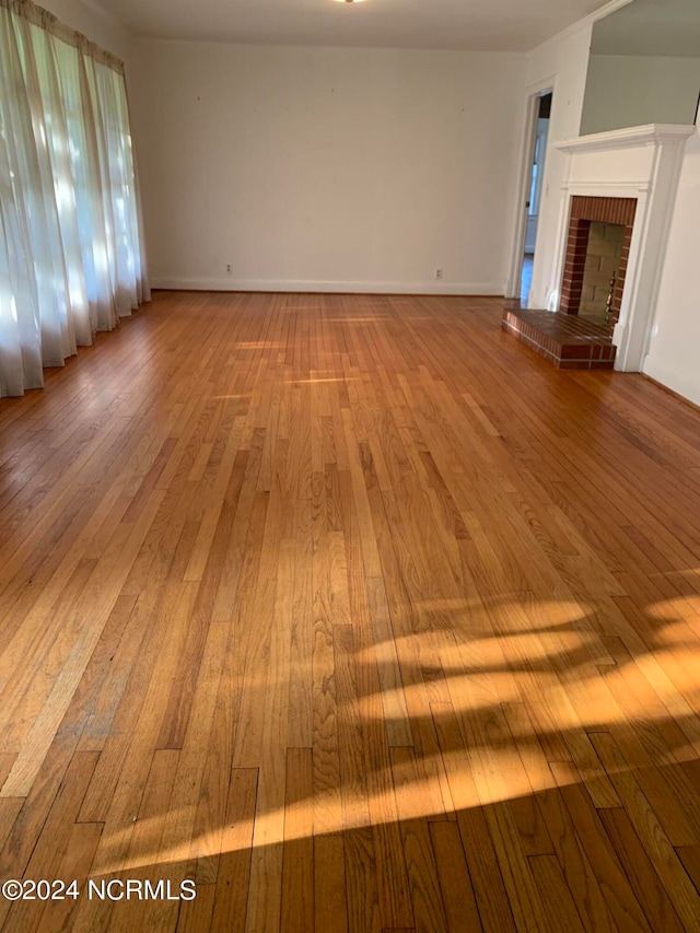 unfurnished living room with light hardwood / wood-style flooring and a brick fireplace