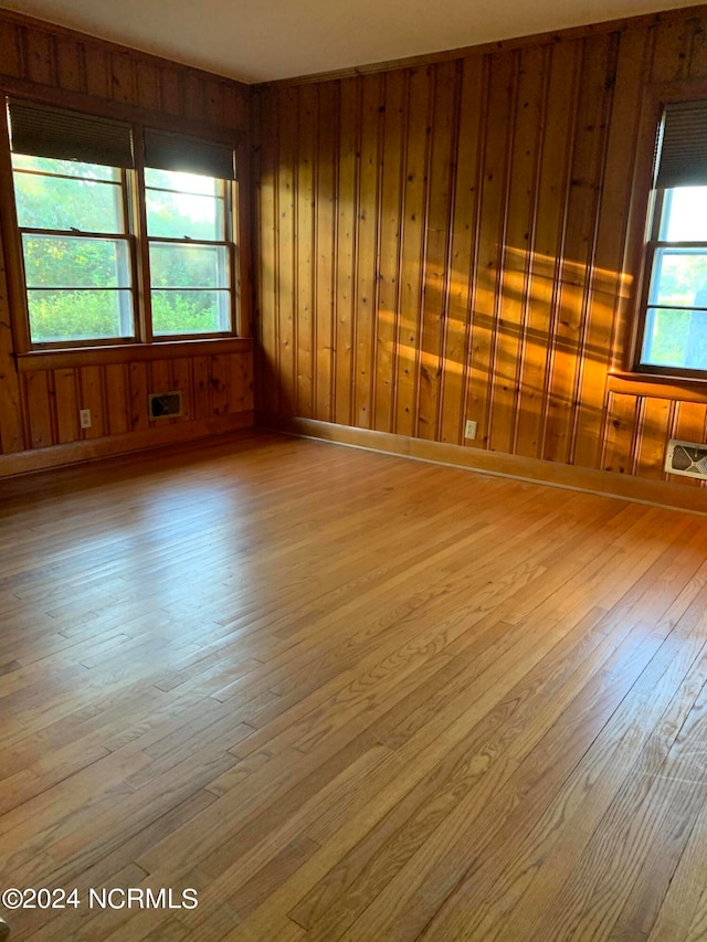 empty room with wooden walls and hardwood / wood-style flooring