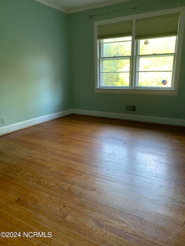 spare room with plenty of natural light, ornamental molding, and hardwood / wood-style flooring