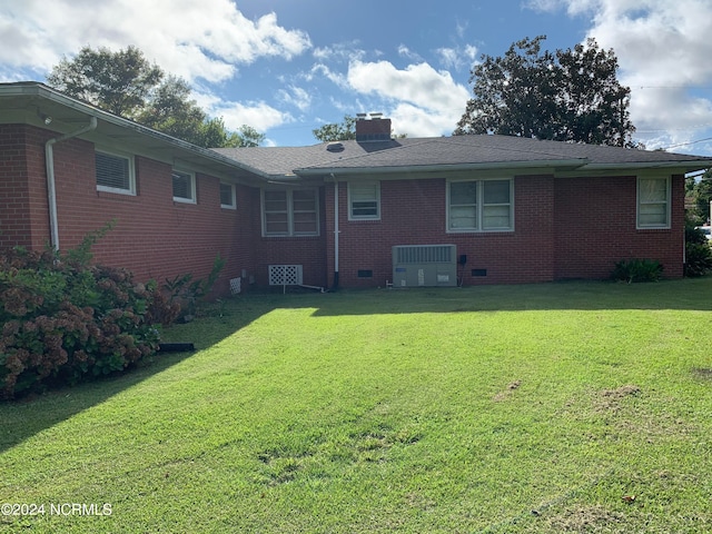 rear view of property with cooling unit and a yard