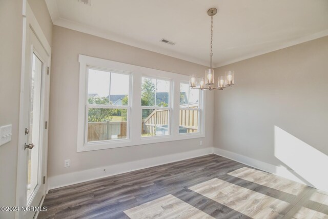 unfurnished dining area with an inviting chandelier, dark wood-type flooring, and crown molding