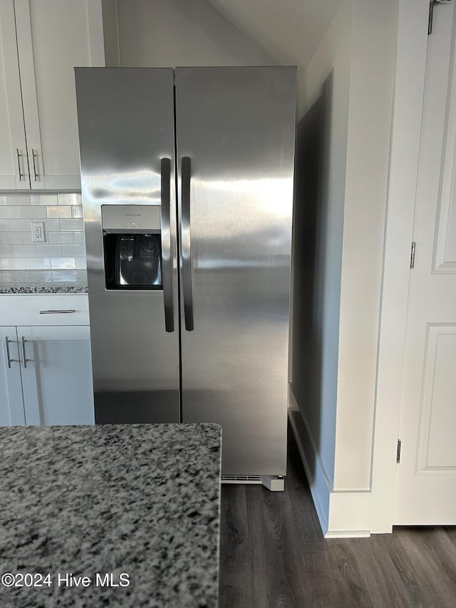 kitchen featuring stainless steel refrigerator with ice dispenser, decorative backsplash, light stone counters, dark hardwood / wood-style flooring, and white cabinetry