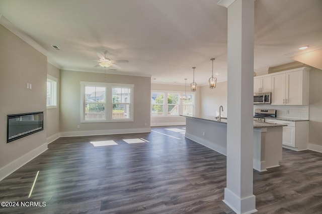 unfurnished living room with dark hardwood / wood-style floors, ornamental molding, and ceiling fan with notable chandelier