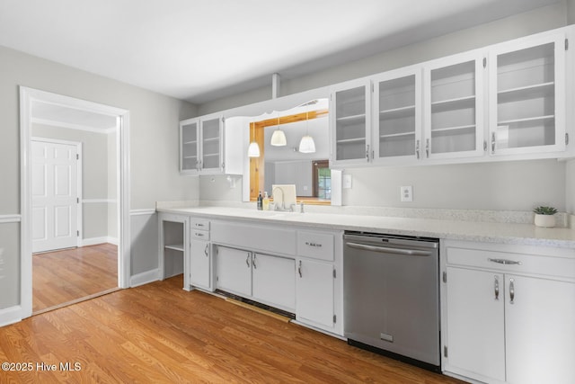 kitchen with stainless steel dishwasher, light wood finished floors, light countertops, and white cabinetry