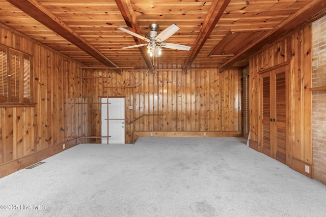empty room featuring ceiling fan, wood ceiling, carpet flooring, wooden walls, and beam ceiling
