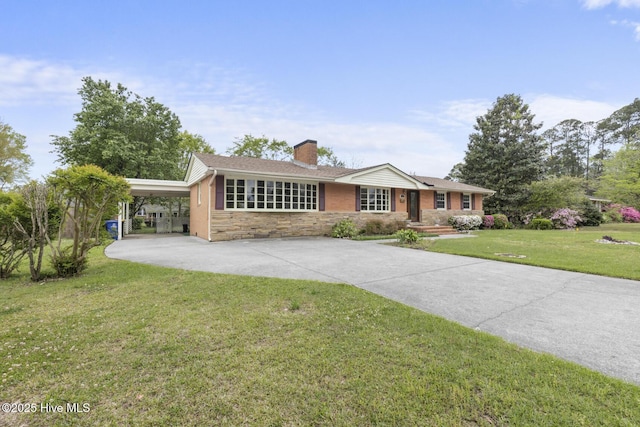 single story home with a front yard, a carport, stone siding, a chimney, and concrete driveway
