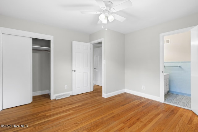 unfurnished bedroom with visible vents, light wood-type flooring, a closet, and ensuite bathroom