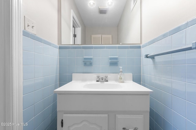 bathroom featuring vanity and tile walls
