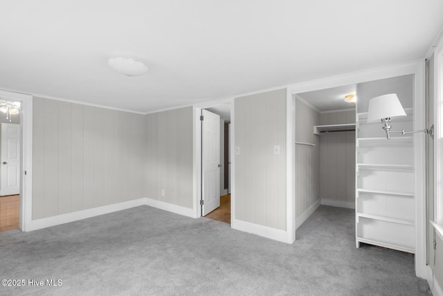 unfurnished bedroom featuring a spacious closet, carpet, baseboards, and ornamental molding