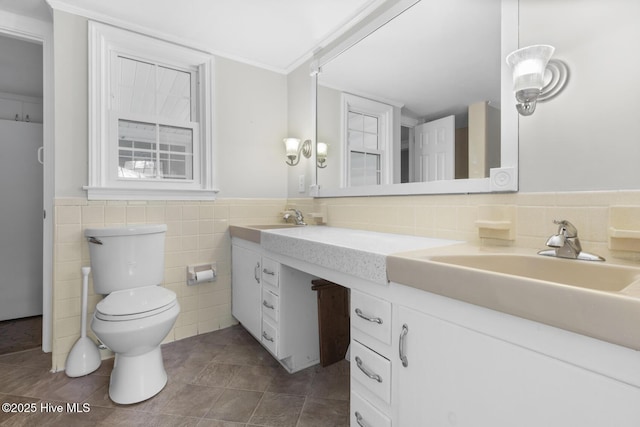 bathroom with a sink, tile walls, double vanity, and toilet