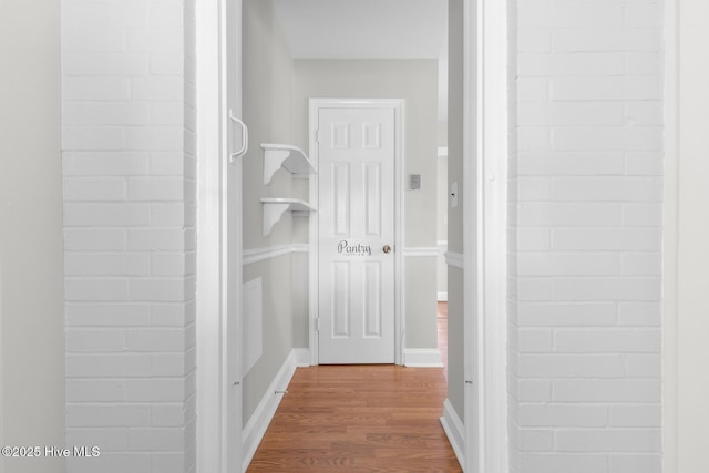 hall with baseboards and wood finished floors