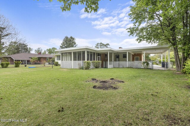 rear view of house with fence, a yard, a sunroom, and a gate