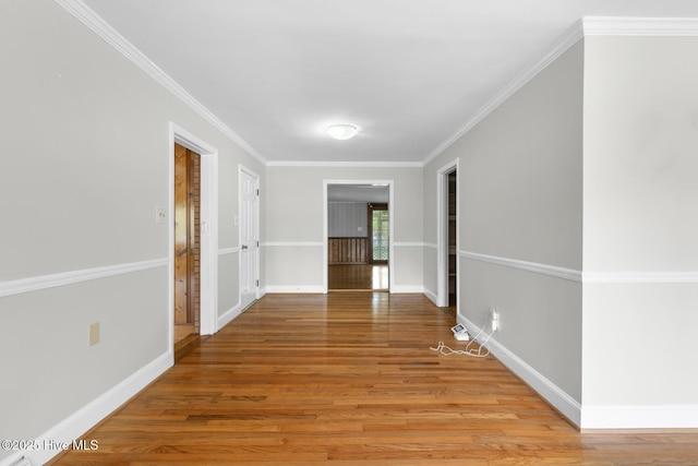 hallway with light wood-style flooring, crown molding, and baseboards