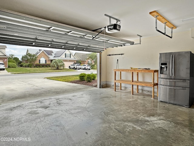 garage with stainless steel refrigerator with ice dispenser and a garage door opener