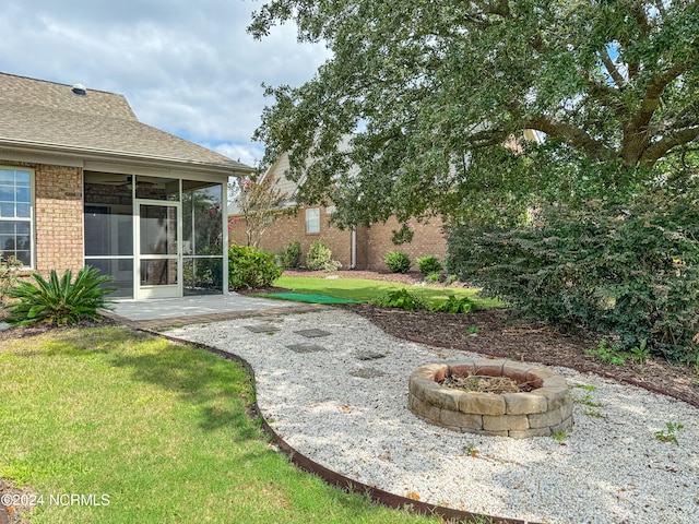 view of yard featuring a fire pit and a sunroom