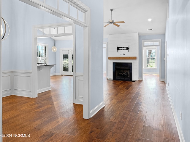 corridor featuring a wealth of natural light, dark hardwood / wood-style flooring, and a towering ceiling