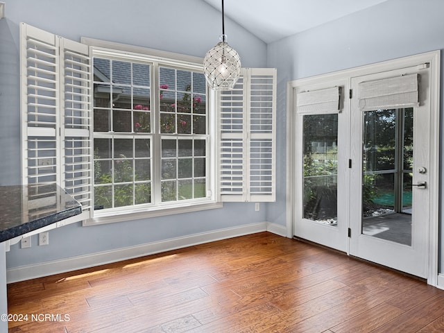 unfurnished dining area featuring vaulted ceiling and dark hardwood / wood-style floors