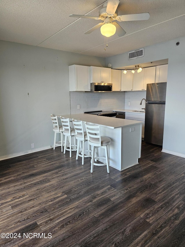 kitchen with a breakfast bar, stainless steel appliances, visible vents, a sink, and a peninsula