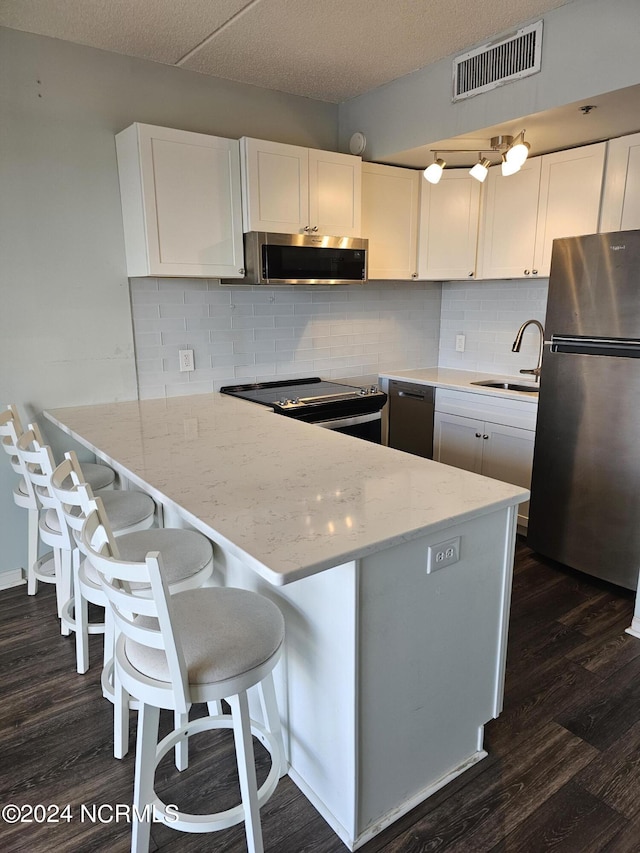 kitchen featuring visible vents, white cabinets, dark wood finished floors, appliances with stainless steel finishes, and a sink