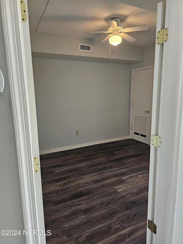 unfurnished room with a textured ceiling, dark wood-style floors, and visible vents