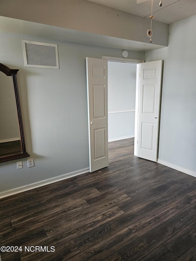 spare room with baseboards, dark wood finished floors, and a textured ceiling