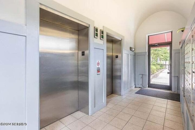 interior space featuring lofted ceiling, light tile patterned flooring, and elevator